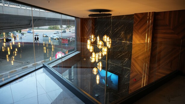A modern lobby with a glass floor, a marble wall, and a wooden panel design. - Kent Room Hotel (Kapaklı)