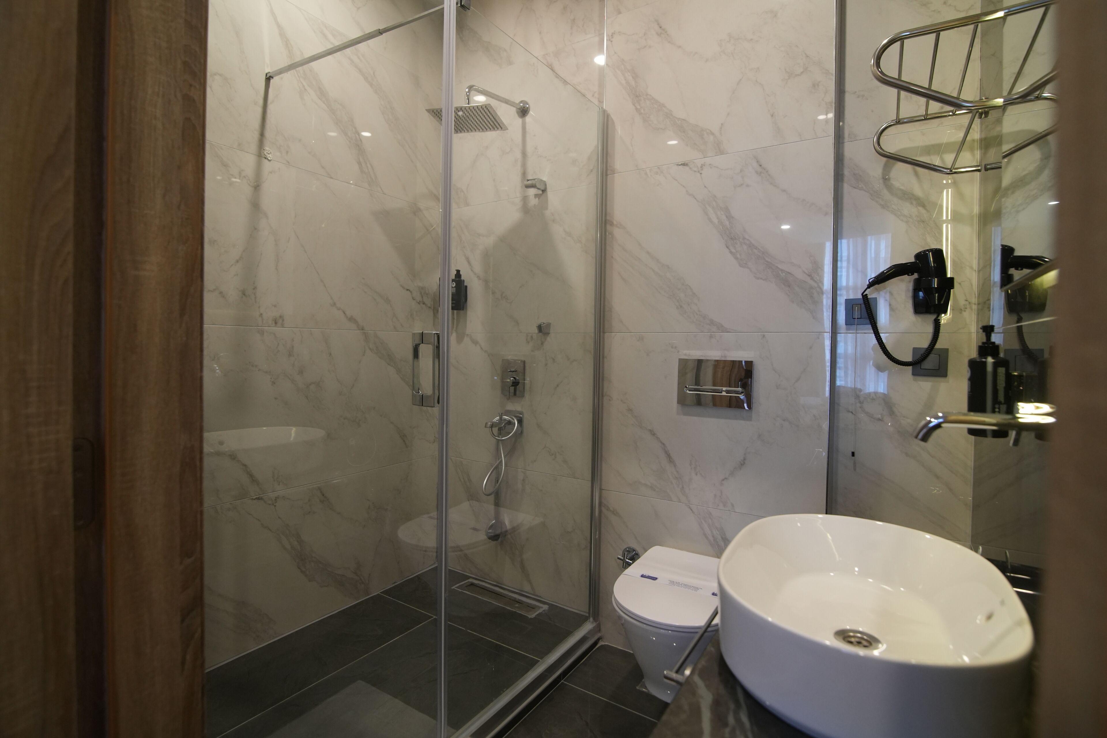 Un baño moderno con ducha de vidrio, un lavamanos blanco y un inodoro.
