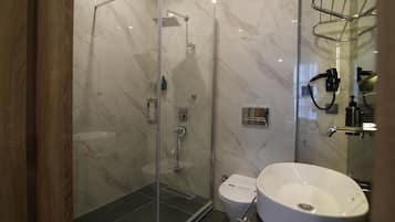 Un baño moderno con ducha de vidrio, un lavamanos blanco y un inodoro.