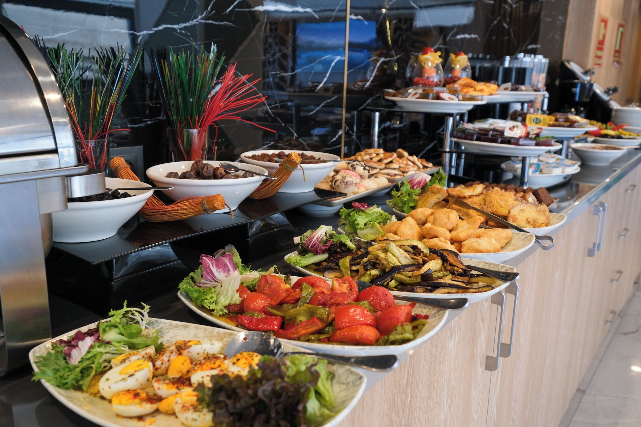 A buffet with various dishes including salads, vegetables, and fried items.