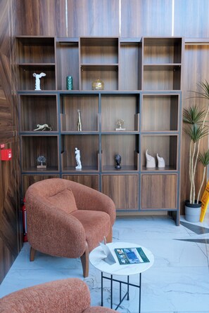 Un interno moderno con una parete in legno, una poltrona marrone, un piccolo tavolino rotondo e una libreria con diversi oggetti decorativi.