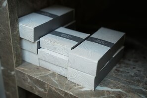 A stack of white boxes with a wood grain pattern and text on them, placed on a marble surface. - Kent Room Hotel (Kapaklı)