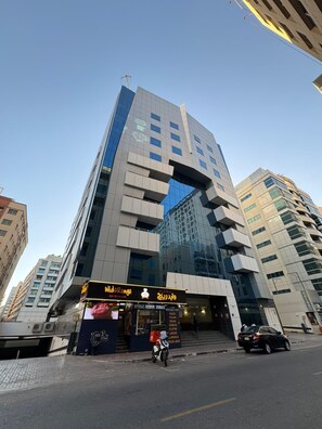 A modern building with a unique architectural design, featuring a large glass facade and a distinctive entrance. - Avari Al Barsha Apartment Hotel (Dubai)