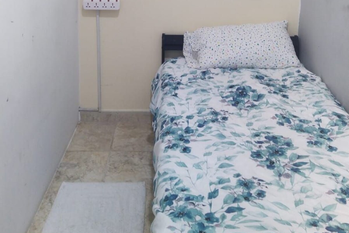 Ein kleines Schlafzimmer mit einem Bett, einer Wandsteckdose und einer Steckdose.