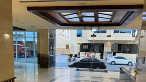 A spacious lobby with a checkered floor pattern, a glass entrance, and a view of the street outside. - Avari Al Barsha Apartment Hotel (Dubai)