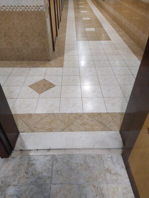 A corridor with tiled flooring, a patterned tile design, and a staircase leading down. - Avari Al Barsha Apartment Hotel (Dubai)