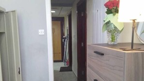 A bedroom with a bed, a dresser, and a lamp with a vase of flowers. - Avari Al Barsha Apartment Hotel (Dubai)