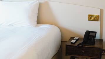 Ein Hotelzimmer mit einem Bett, einem Nachttisch mit Telefon und einer Steckdose.