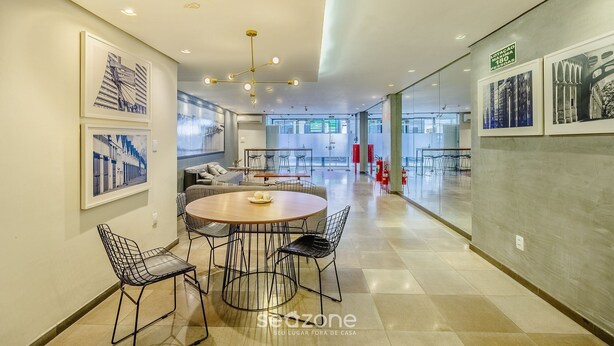 Un interior moderno con una mesa de comedor redonda, sillas de estructura de alambre negro y una lámpara de techo.