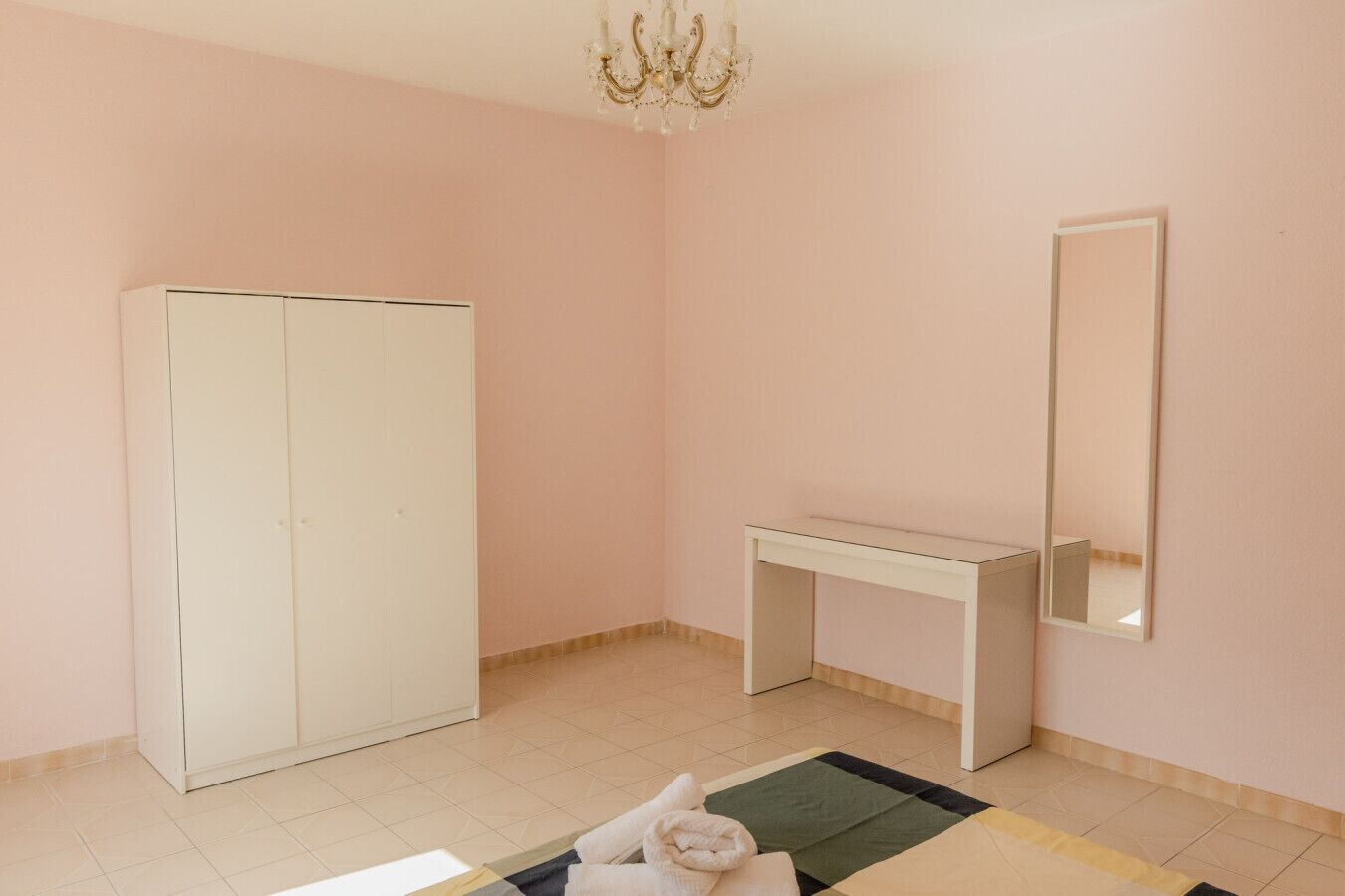 A room with a wardrobe, a desk, and a mirror.
