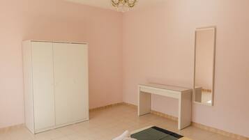 A room with a wardrobe, a desk, and a mirror.