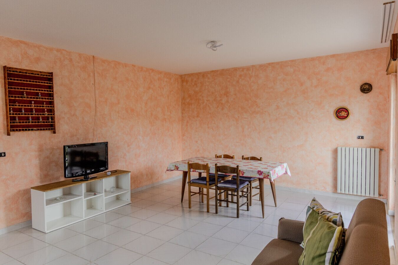 Un salon avec un téléviseur, une table à manger avec des chaises et un canapé.