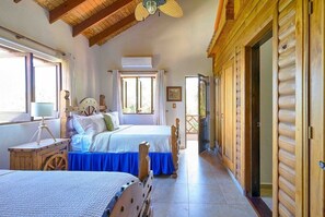 Ein Zimmer mit zwei Betten, Holzmöbeln, einem Deckenventilator und einem großen Fenster.