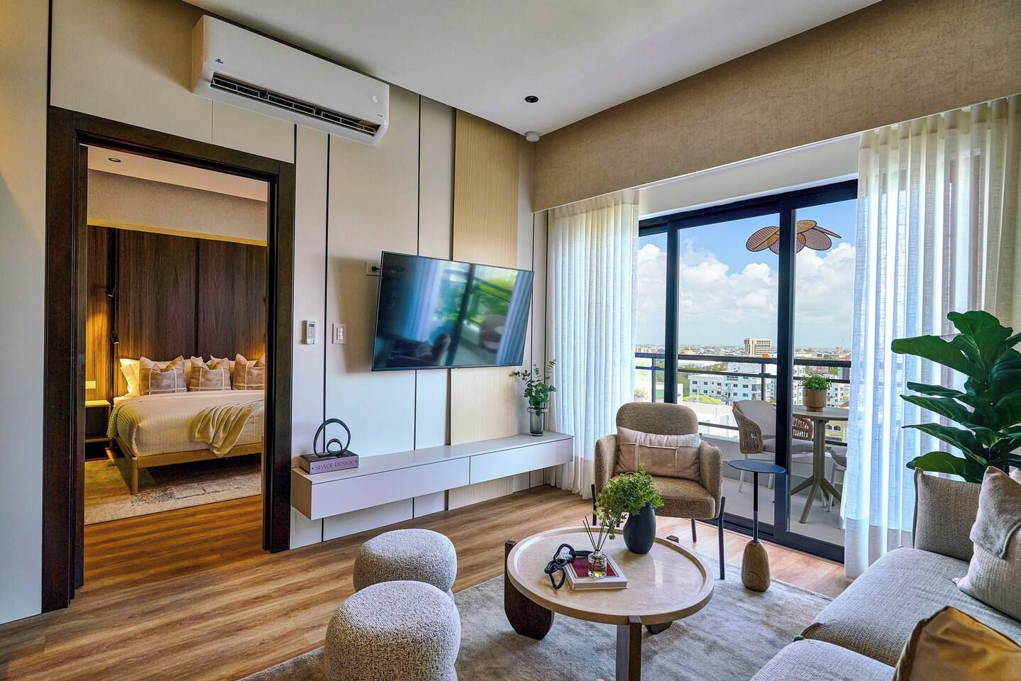 Habitación de hotel con cama, televisión, zona de estar con mesa y balcón con vistas.