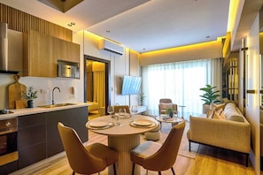 A modern kitchen with a central island, dining area with round table and chairs, and a living space with a sofa and TV. - ®{The~City~LUX~Place} @DowtownSD +Pool+Gym+Games (Santo Domingo)