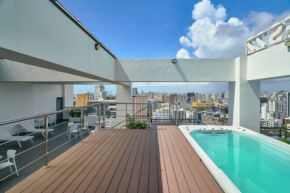Una terrazza panoramica sul tetto con piscina, lettini e vista sulla città.