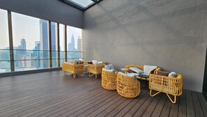 Quarto em um prédio alto com vista para a cidade, janelas amplas e móveis de vime.
