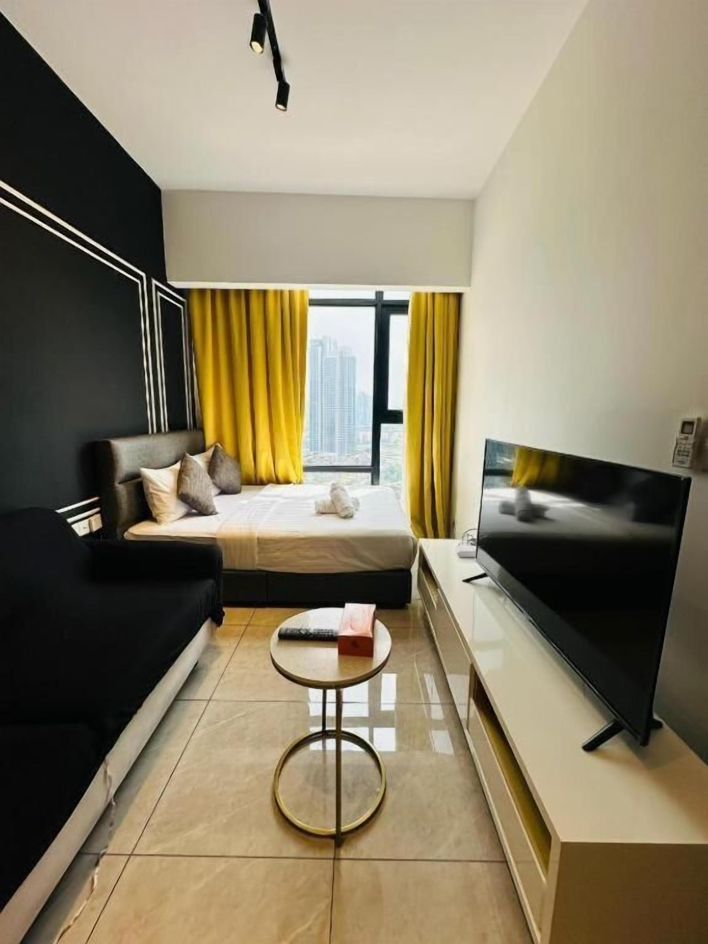 A modern hotel room with a bed, a sofa, a TV, and a window with curtains.