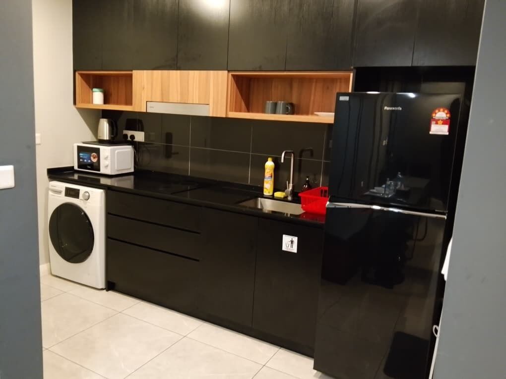 Una cocina moderna con encimera negra, microondas, lavadora y refrigerador.