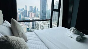 Quarto de hotel com uma grande janela e vista para o horizonte da cidade.