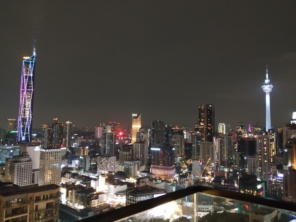 A nighttime cityscape with illuminated skyscrapers and a prominent tower.