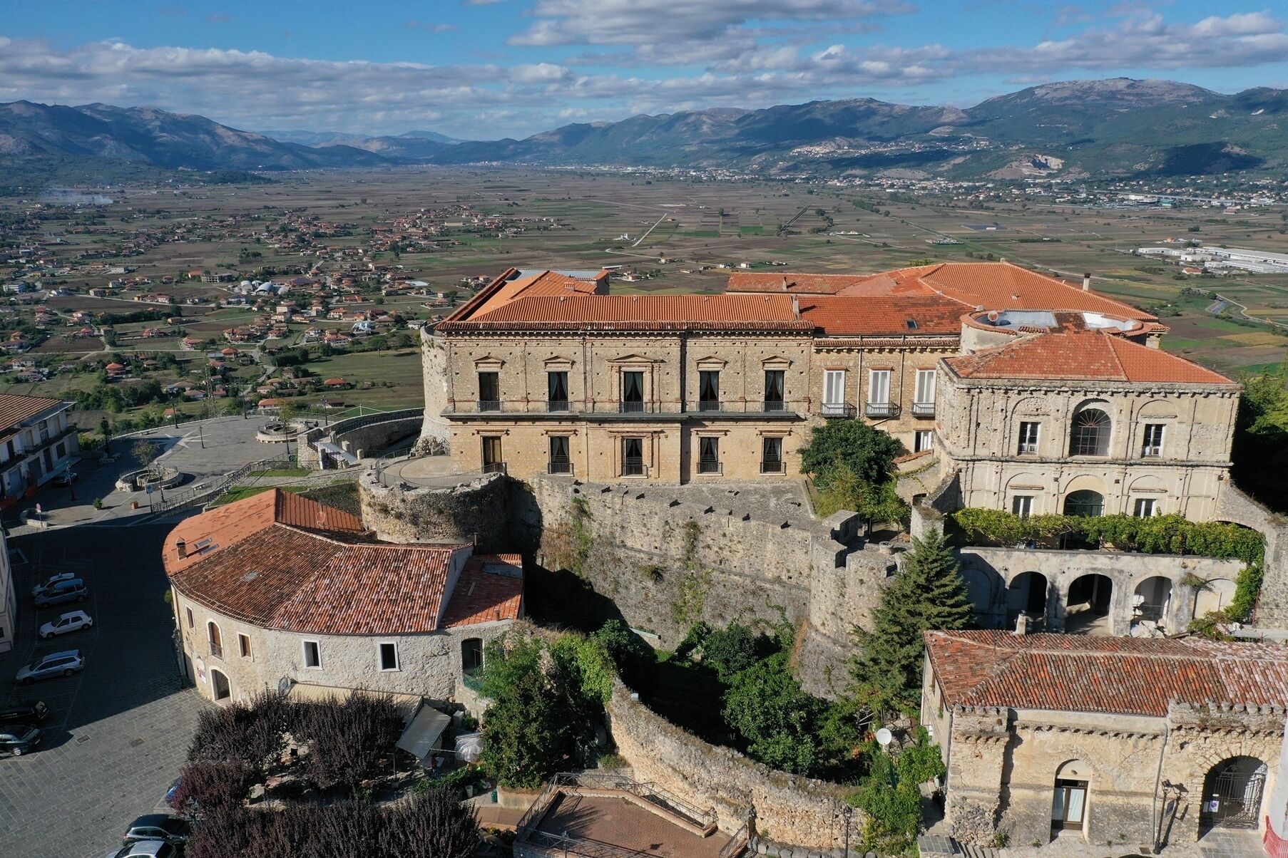 Un edificio storico con un cortile, pareti in pietra e un tetto in tegole rosse.