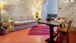 A cozy room with a stone wall, a wooden table, a sofa, and a lamp. - L' Armoniosa the magic of the medieval Macchiaroli Castle in Teggiano (Teggiano)