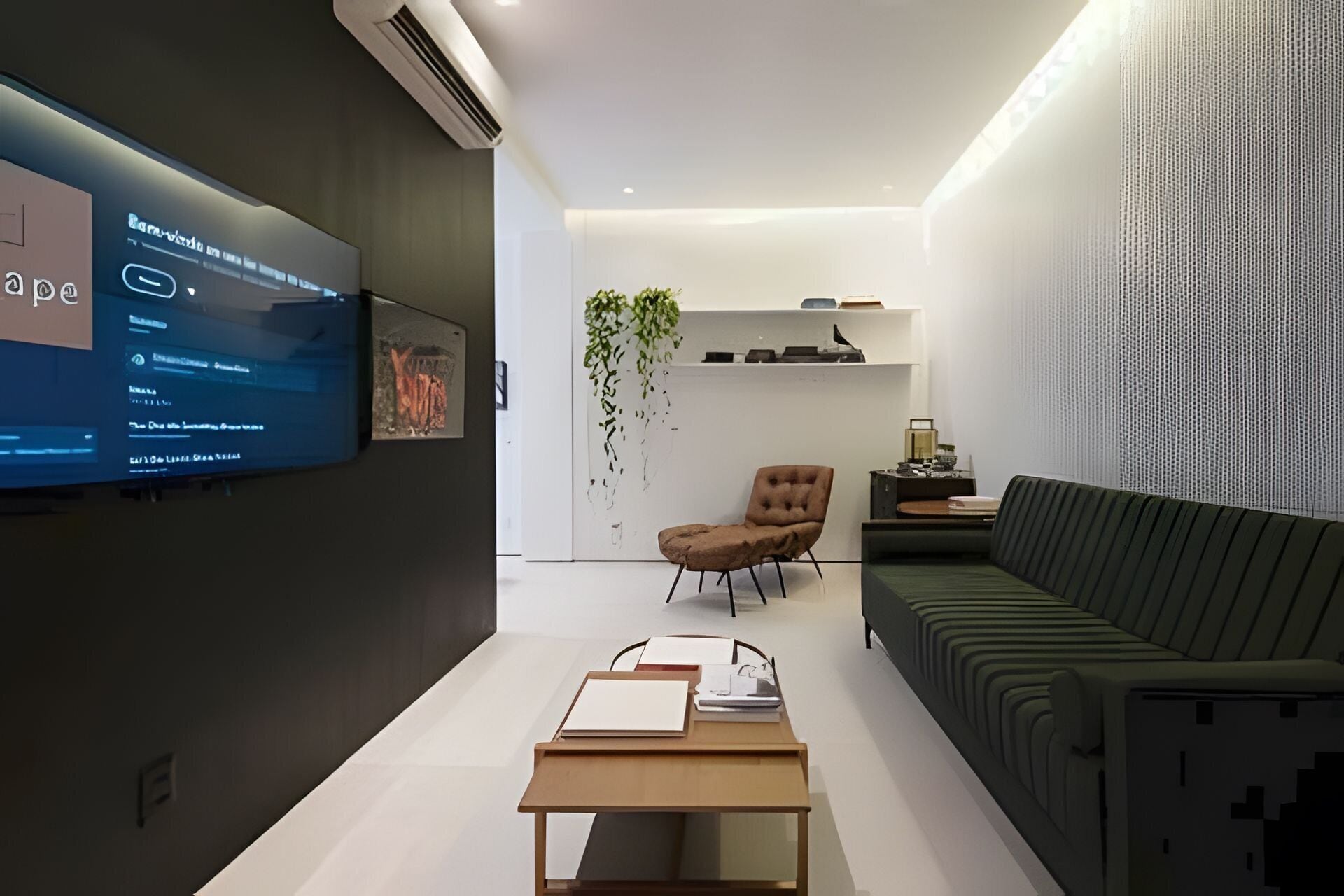 A modern living room with a flat-screen TV mounted on the wall, a sofa, a chair, and a coffee table.