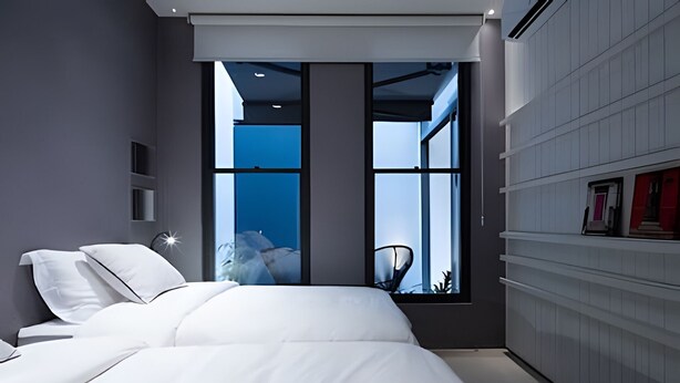 Ein modernes Schlafzimmer mit einem großen Bett, Blick zum Himmel durch ein Fenster und einem integrierten Kleiderschrank.