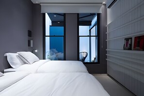 A modern bedroom with a large bed, a view of the sky through a window, and a built-in wardrobe. - Ipanema | Suíte ampla, em uma das melhores ruas do Bairro, 5 min da Praia - por Casapē Rio (Rio de Janeiro)