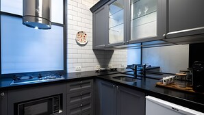 Eine moderne Küche mit grauen Schränken, einer schwarzen Arbeitsplatte und einem eingebauten Backofen.