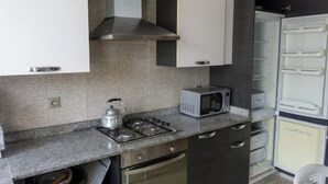 Une cuisine compacte équipée d’une cuisinière à gaz, d’un four à micro-ondes et d’un four encastré.