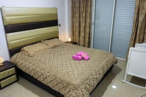A bedroom with a bed, a nightstand, a lamp, and a wardrobe. - Spacious apartment: Comfort, Parking and Wi-Fi. (Agadir)