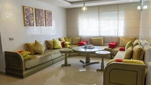 Un salon spacieux comprenant un grand canapé, une table basse ronde et un lit.