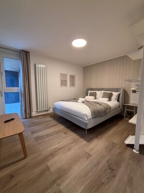 Ein modernes Schlafzimmer mit einem Bett, einem Nachttisch und einem Fenster mit Vorhängen.