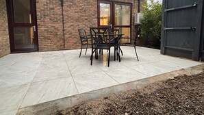 A patio with a brick wall, a glass door, and a table with chairs.