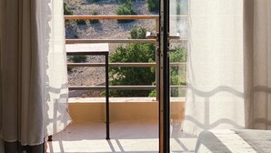 Une pièce dotée d’une grande fenêtre, d’une balustrade en bois et offrant une vue sur un paysage rocheux à la végétation clairsemée.