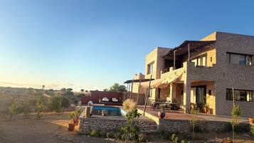 A modern two-story house with a stone facade, a swimming pool, and outdoor furniture.