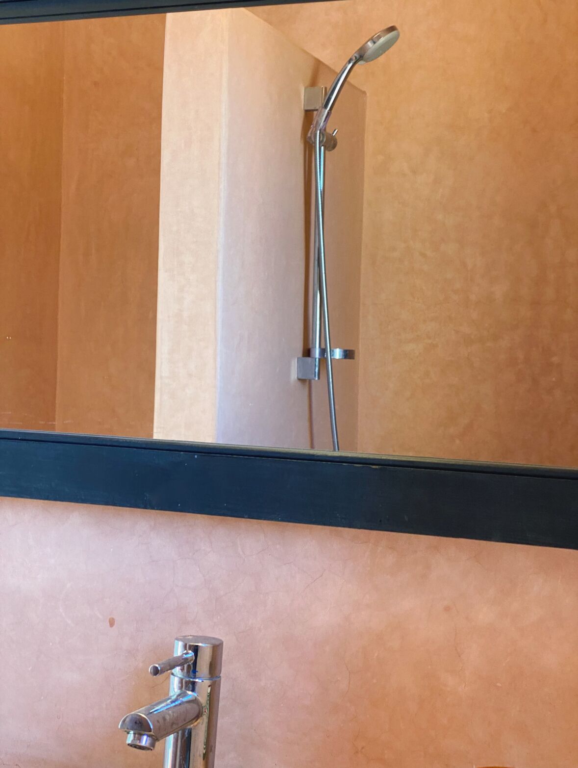 Un baño con ducha, espejo y lavamanos.