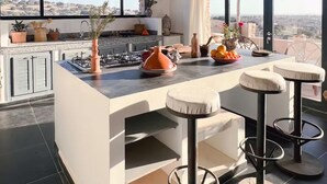 Une cuisine moderne dotée d’un grand îlot central, de tabourets de bar et offrant une vue sur la ville.