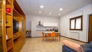 A modern kitchen with white cabinets, a dining table with orange chairs, and a blue sofa with a cushion. - The Orchid - Francavilla al Mare (Francavilla al Mare)