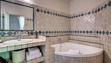 Un baño con dos lavamanos, una bañera y un espejo.