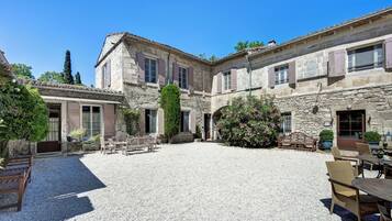 A courtyard with stone buildings, outdoor seating, and potted plants.
