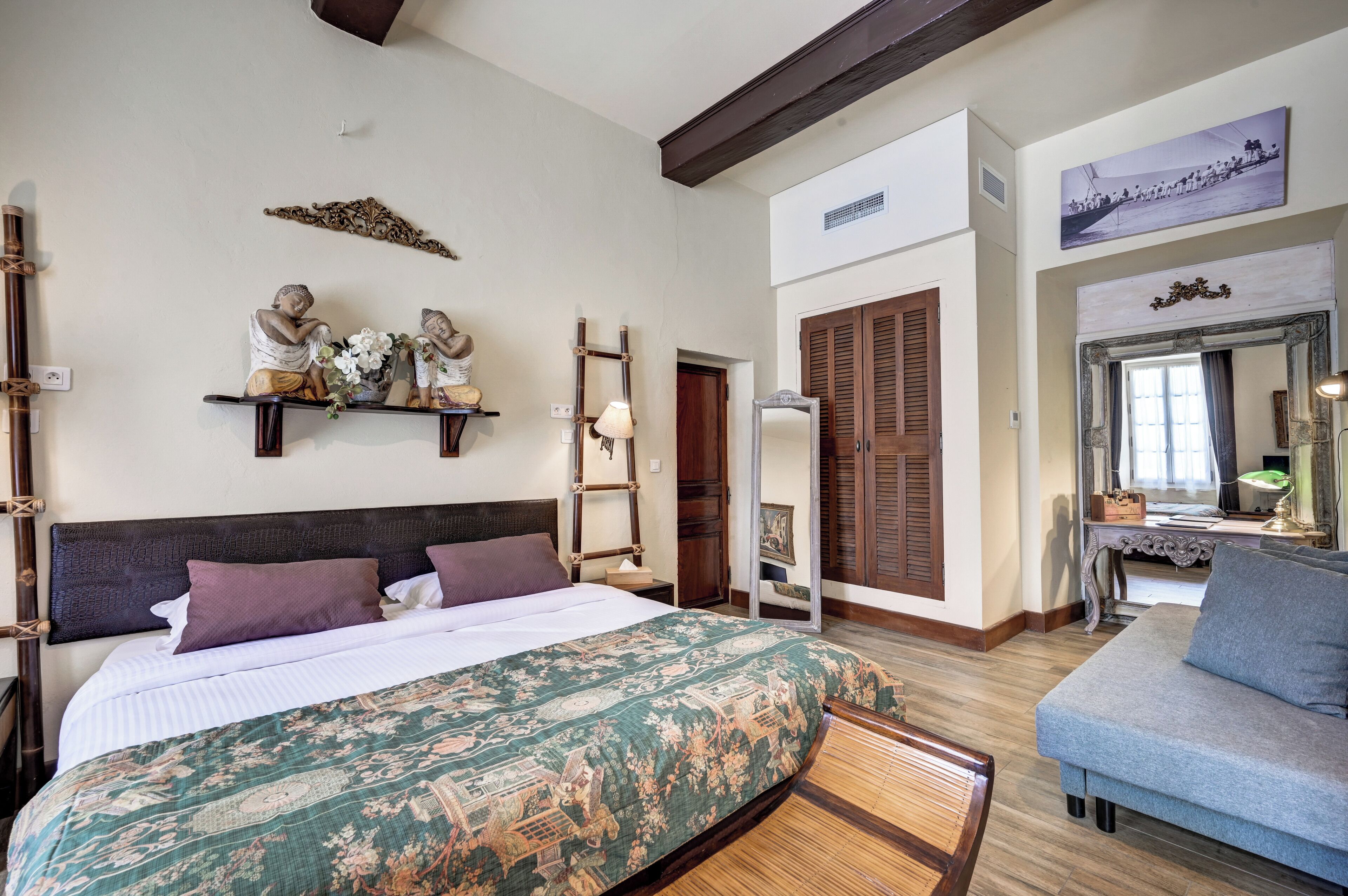 Une chambre à coucher comprenant un lit, une table de chevet, une chaise, un miroir et une étagère avec des objets décoratifs.