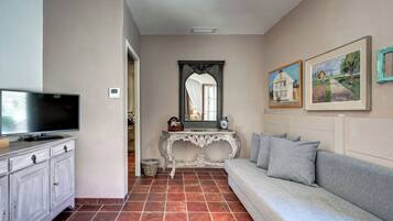 Una sala de estar con televisor, sofá, mesa consola y espejo.