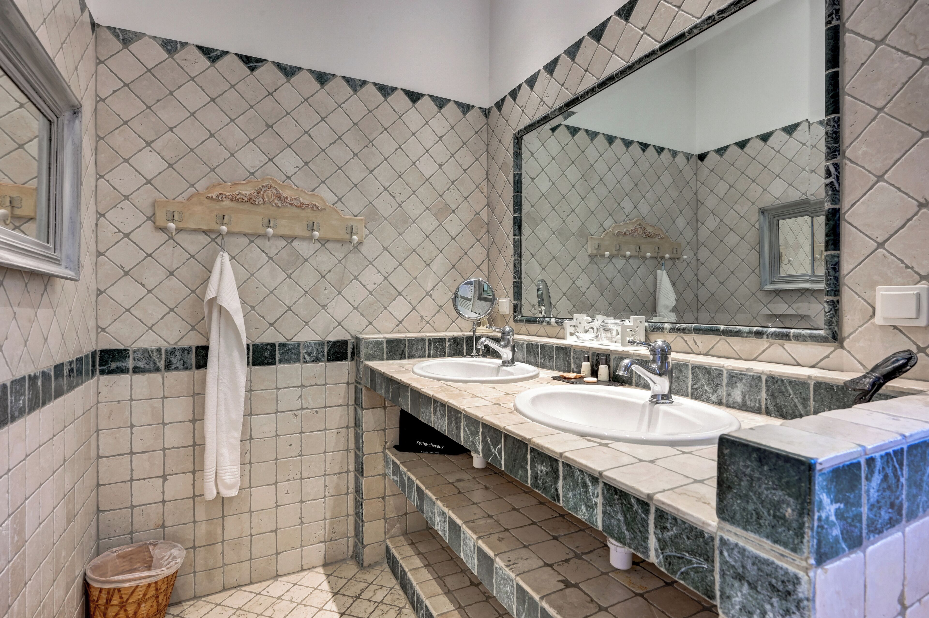 Un baño con dos lavamanos, un espejo y un perchero para toallas.