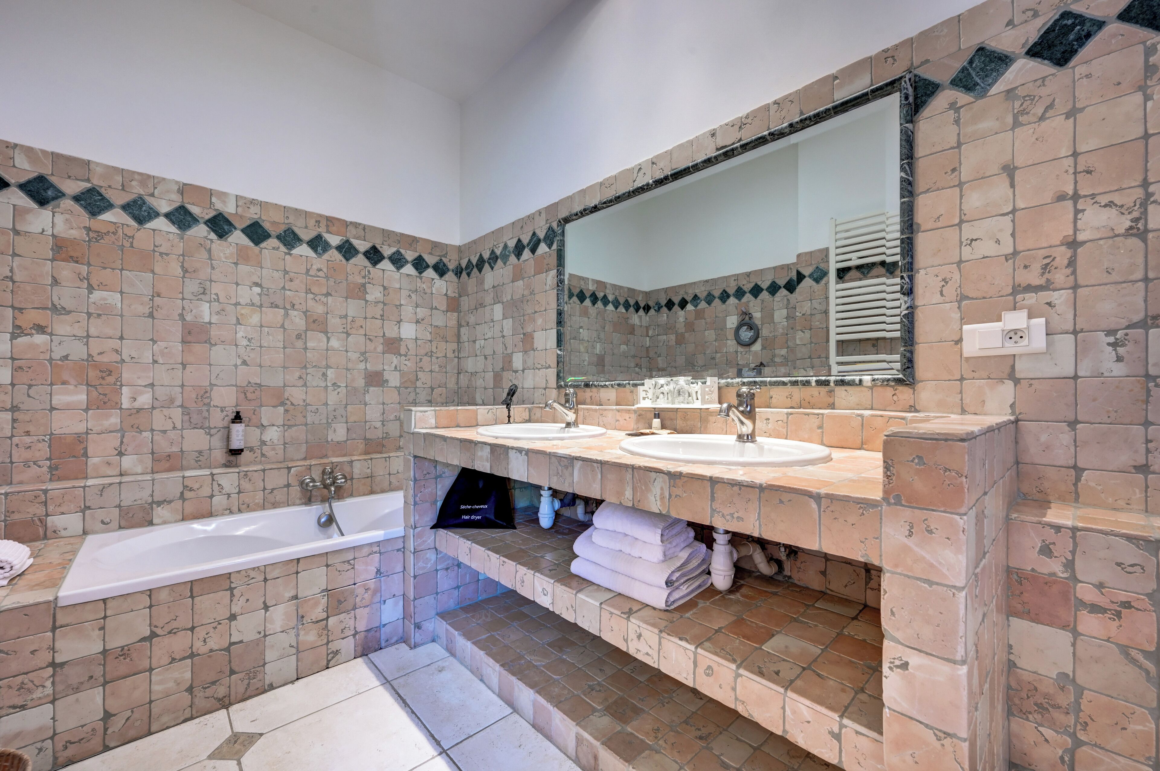 A bathroom with two sinks, a bathtub, and a large mirror.