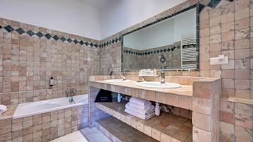 A bathroom with two sinks, a bathtub, and a large mirror.
