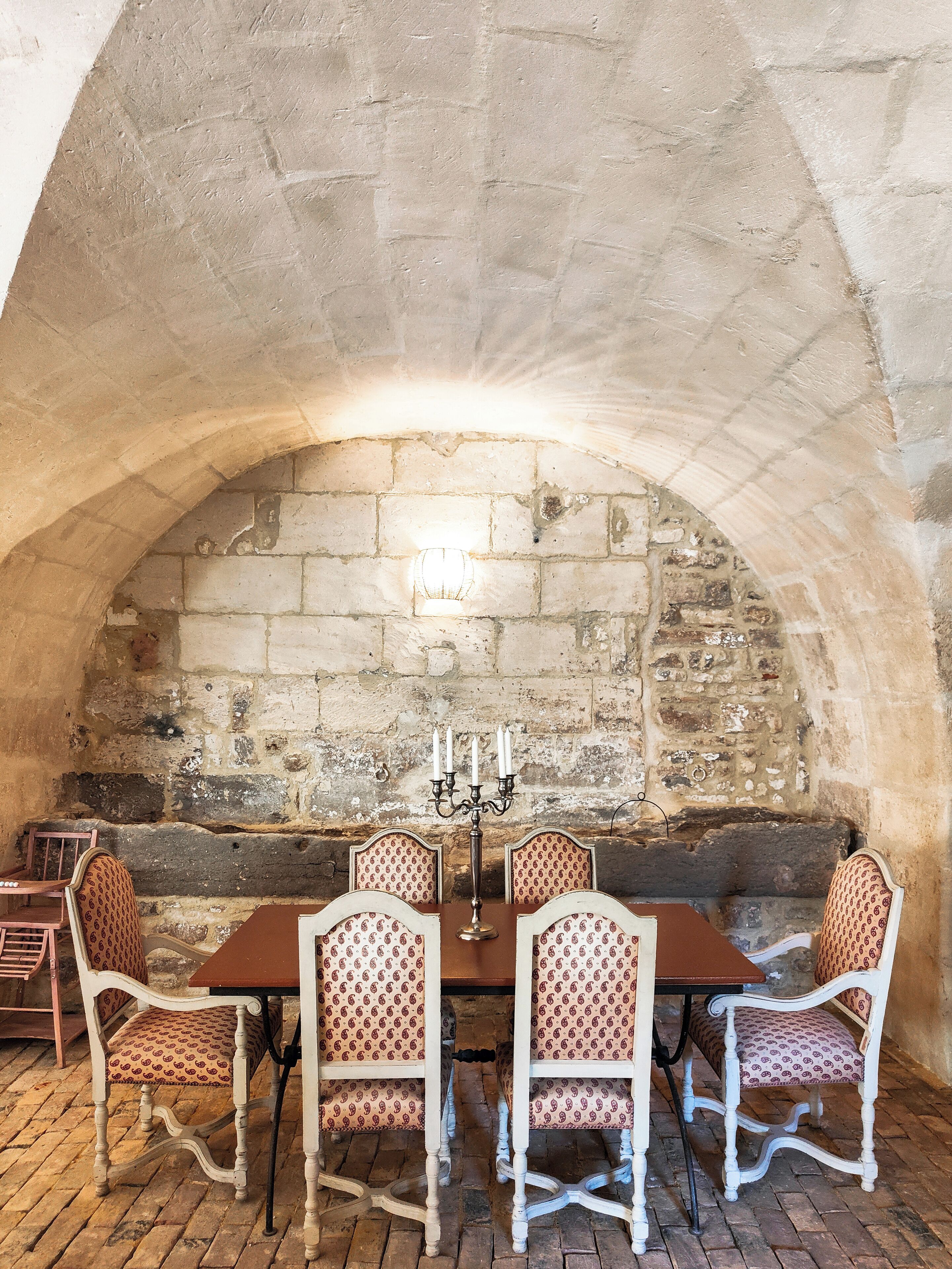 Un comedor con pared de piedra, una mesa y cuatro sillas, y un candelabro.
