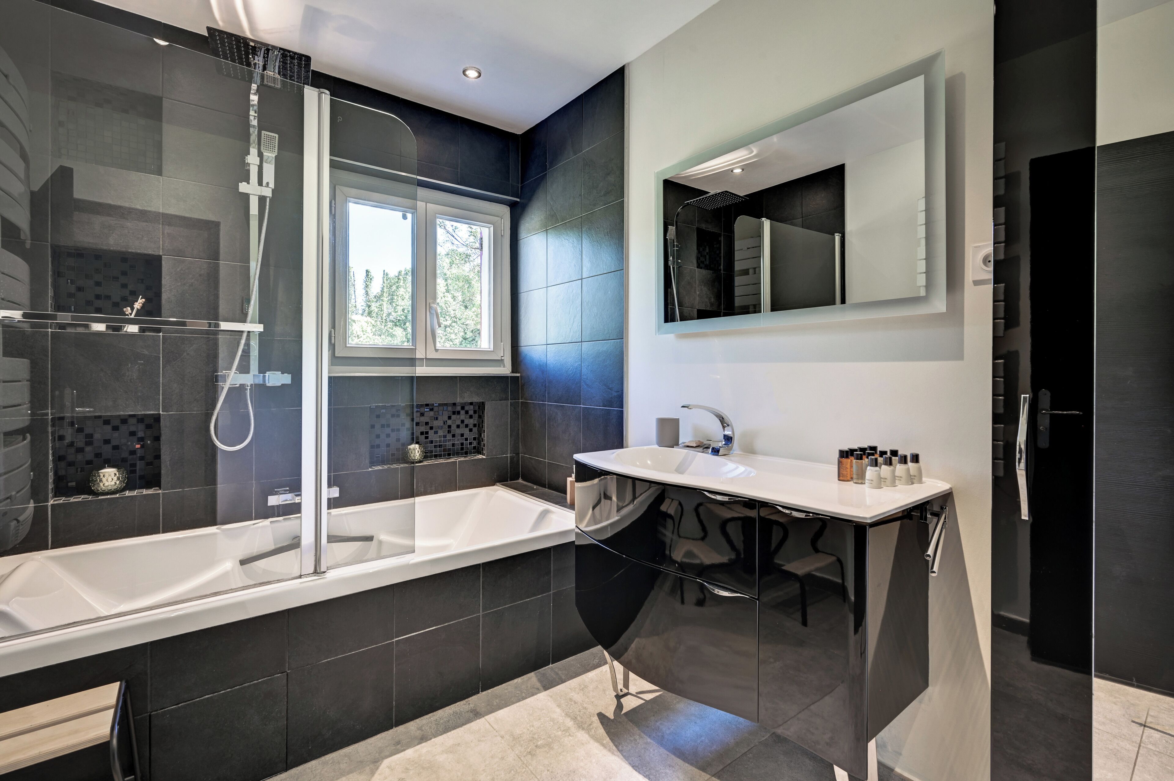 A modern bathroom with a bathtub, shower, and vanity.